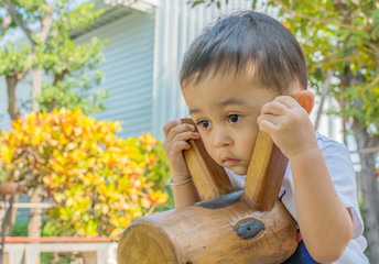 Cute asian boy playing with wooden horse