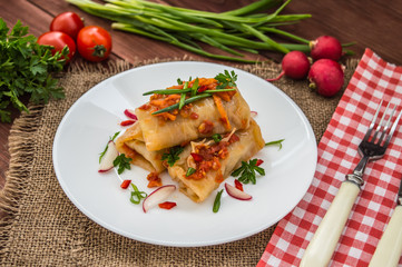 Cabbage rolls in tomato sauce. white plate. wood background.
