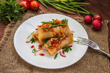 Cabbage rolls in tomato sauce. white plate. wood background.