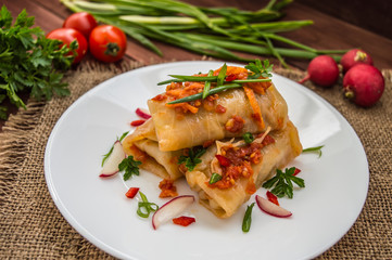 Cabbage rolls in tomato sauce. white plate. wood background.