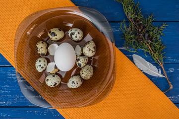 Chicken and quail eggs on a dark transparent plate. Top view