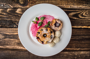 Cheesecakes with cherries and currants covered  powdered sugar on a wooden background. Top view