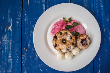 Cheesecakes with cherries and currants covered  powdered sugar on a blue wooden background. Top view