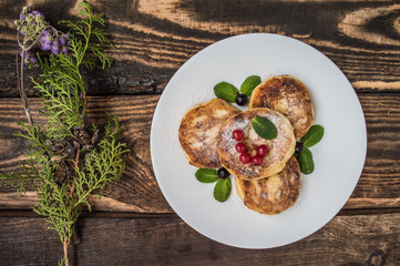 Cheesecakes with currants covered  powdered sugar on a wooden background. Top view