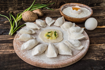 Raw dumplings with potatos on a wooden board. Rustic background