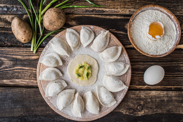 Raw dumplings with potatos on a wooden board. Rustic background. Top view