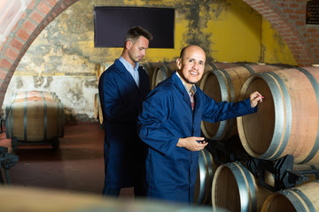 Fototapeta na wymiar two wine makers in winery cellar.