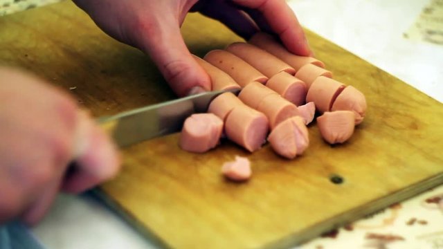 the young man cuts some sausages on the Board