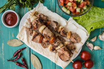 Pork cooked with vegetables on skewers  a turquoise table. Wooden background
