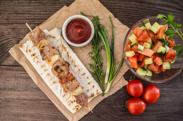Pork cooked with vegetables on skewers  a wooden background
