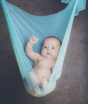Newborn Baby Suspended In Blue Fabric