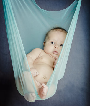 Newborn Baby Suspended In Blue Fabric