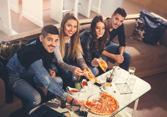 Young people in casual clothes eating pizza, talking