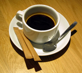 Coffee cup isolated. Coffee cup top view. Cup of coffee on table with sugar and spoon. Wood background.