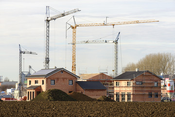 Haus- und Wohnungsbau im Rohbau mit vielen Baukränen