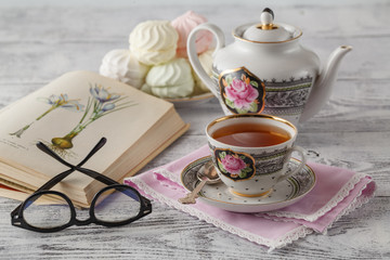 wooden background with Cup of tea and a book on near a teaspoon