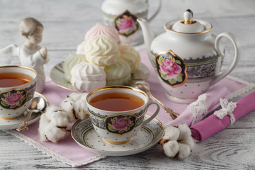 Two cups of hot tea and cotton flowers on rustic concrete backgr