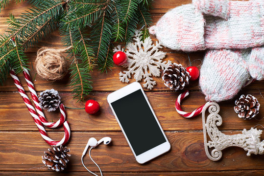 Smart phone mock up with headphones and rustic Christmas decorations for app presentation. View from above