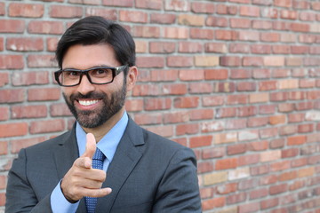 Attractive young businessman pointing a finger towards you