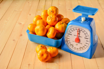 Many oranges in the cart placed beside scales.