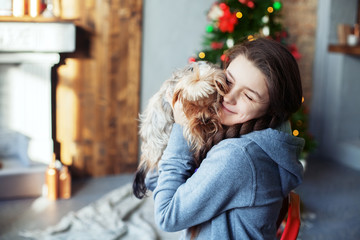 Teen girl hugging a dog. The concept of Christmas