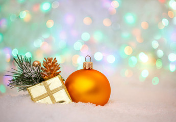 Christmas decoration. yellow ball and golden Gift box on snow