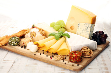 Cheese platter with different cheese and grapes - some emmental, gauda, parmesan and brie cheese on a table for brunch