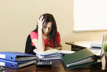 Tired young woman working with documents in the workplace in the office