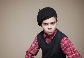 Boy in a beret with a grumpy face.