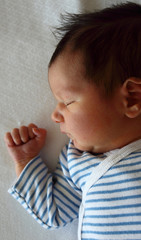 Sweet newborn little baby lying on the bed just two days after arrival.