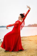 Woman in long red dress stay in dancing pose