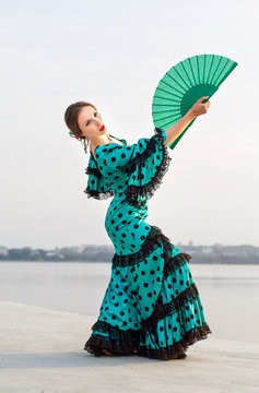 Woman in long green dress stay in dancing pose