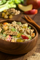 Quinoa Waldorf Salad with apple, celery, yellow raisins and walnut, ingredients in the back, photographed with natural light (Selective Focus, Focus one third into the salad)