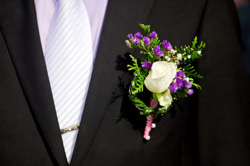 boutonniere of white roses on a black men's suit