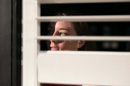 Girl looks through blinds and is worried