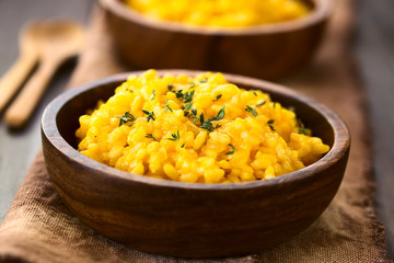 Kürbisrisotto mit frischem Thymian in Holzschüssel, fotografiert mit natürlichem Licht (Selektiver Fokus, Fokus ein Drittel in das Risotto)