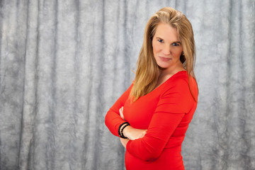 Fototapeta premium Blonde Female In Red Dress with Arms Folded Stern Look