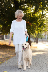 Senior woman walking with dog in park