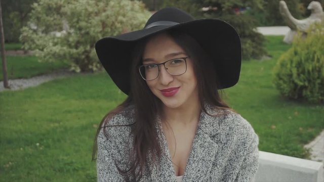 Close up portrait of pretty smiling woman in black hat and glasses in the park outdoor HD