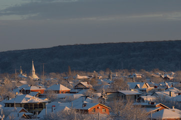 Orthodox Church among the single-storey houses. Winter evening.