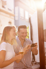 Laughing couple with cellphone and beers