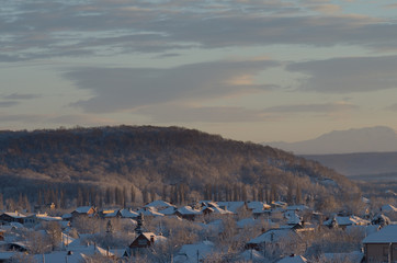 Зимний пригород на фоне холмов и го