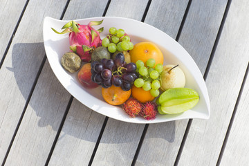 Tropical fruit on a white plate on a wooden surface.