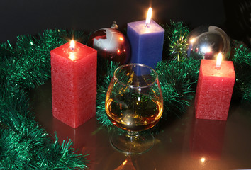 Glass of brandy or cognac and candle on the wooden table