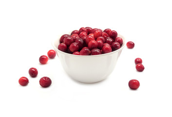 Cranberries in round white bowl and scattered berries isolated on white background indoor front view close up