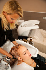 Hair stylist at work - hairdresser washing hair to the customer
