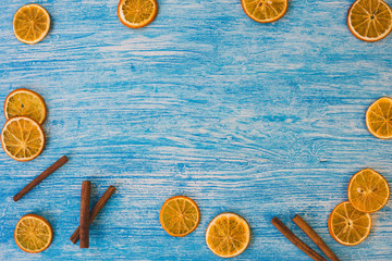 Orange slices and cinnamon on blue wooden background. View with copy space.