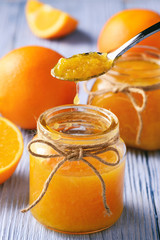 Orange jam in glass jar on wooden background.