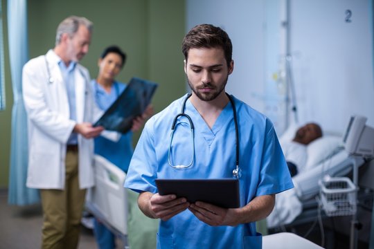 Male nurse using digital tablet in ward