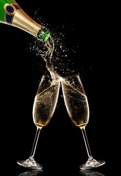 Two glasses of champagne with bottle over black background
